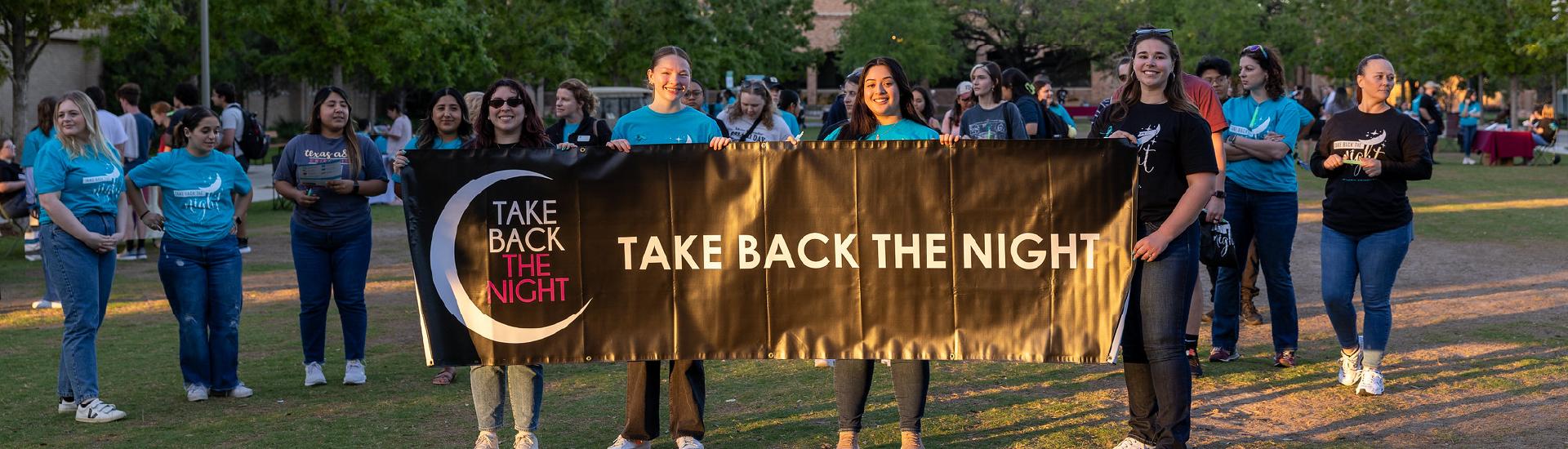 A group of students holding a "Take Back the Night" banner.