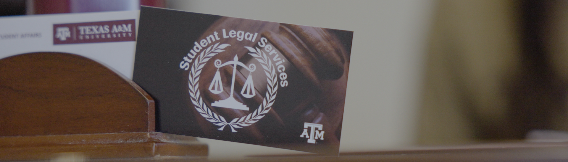 Student Legal Services business card propped up on a wooden desk.