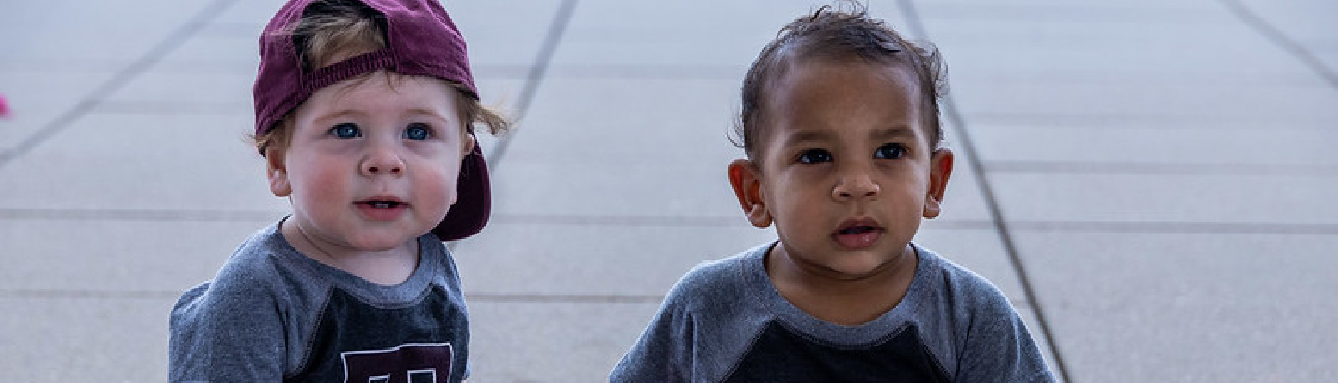 Two toddlers, about one year old each, in Texas A&M shirts.