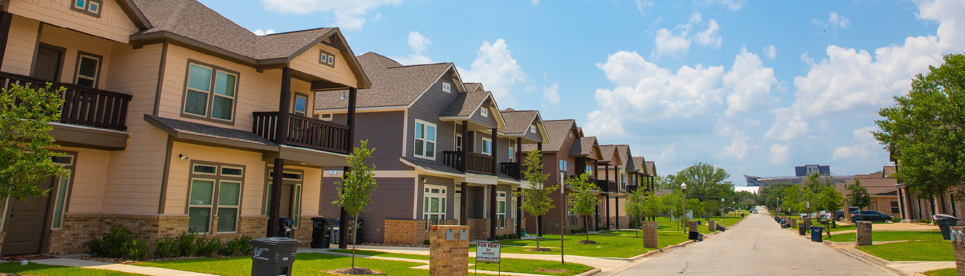 A row of houses with Kyle Field visible just at the end of the street.