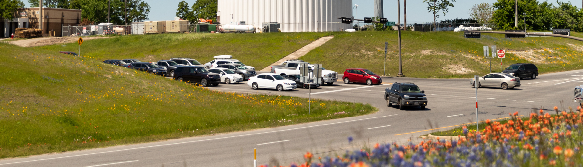 A few lanes of traffic with vehicles sitting at a traffic light.