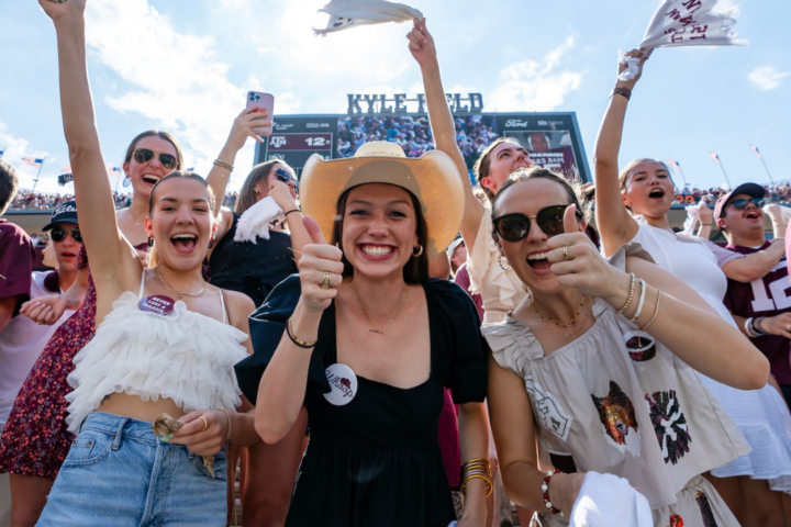 A group of students smiling at Kyle Field while cheering on the Aggie football team.