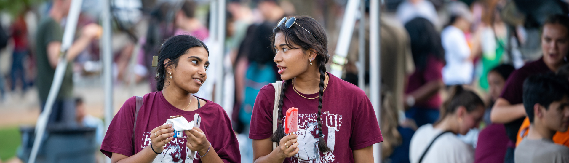 Two students walking and chatting to each other while eating ice cream.